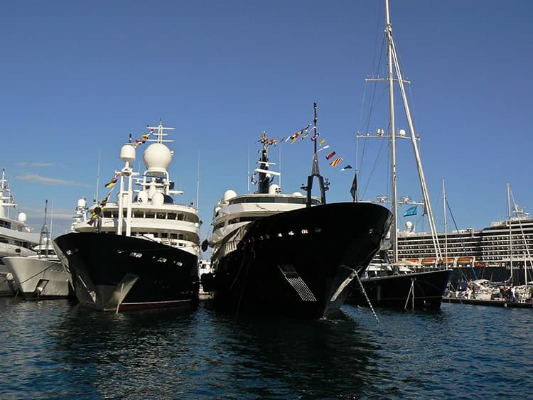 Superyachts moored side by side in a Mediterranean harbour, dressed with signal flags