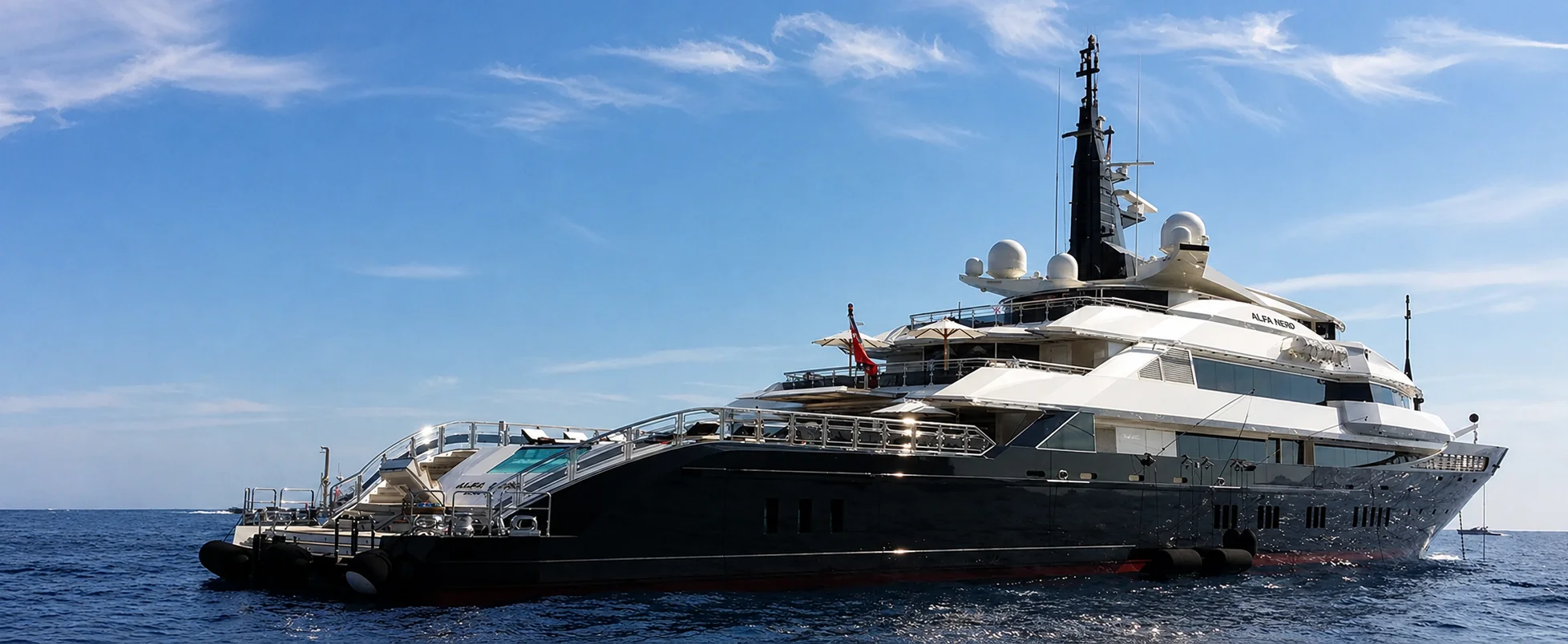 A superyacht anchored on open water under a clear blue sky